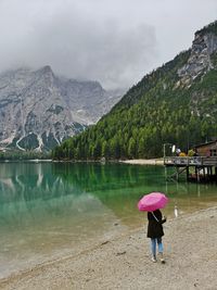 Woman with umbrella walking at lakeshore
