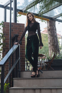 Portrait of woman standing against railing