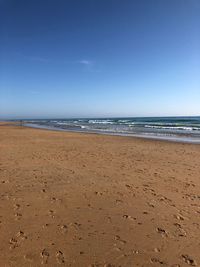 Scenic view of beach against clear blue sky