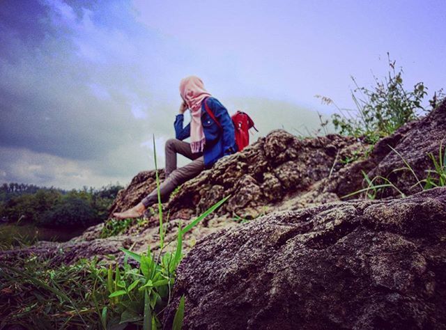 lifestyles, sky, leisure activity, rock - object, full length, casual clothing, mountain, young adult, rock formation, standing, tranquility, tranquil scene, cloud - sky, nature, rock, low angle view, person, tree