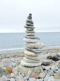 Stack of pebbles on beach against sky