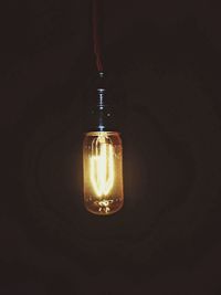 Close-up of lit light bulb in dark room