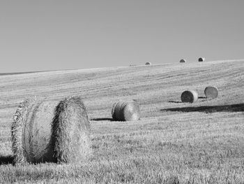 Hay bales on field against clear sky