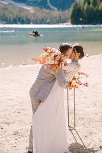 Couple kissing while standing at riverbank