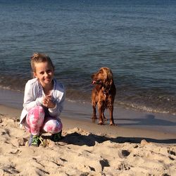 Portrait of girl with dog at beach