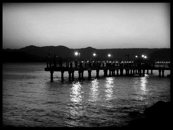 Pier in sea at sunset