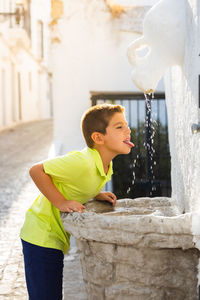 Thirsty kid drinking of an ancient fountain