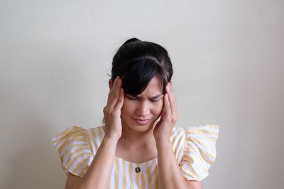 Portrait of smiling young woman against wall