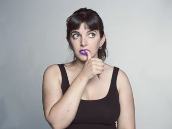 Studio shot of young woman biting her nail