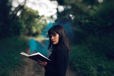 Young woman standing against trees