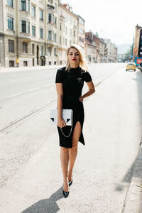 Fashionable woman standing against buildings in city