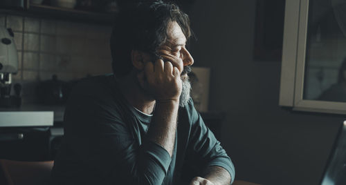 Side view of man looking away while sitting at home