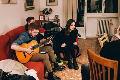 People playing guitar on sofa at home