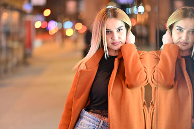 Portrait of young woman standing on street in city