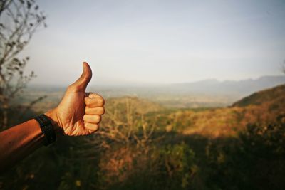 Thumb up midsection of person against sky