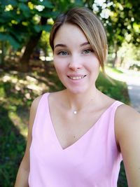 Portrait of smiling young woman against trees