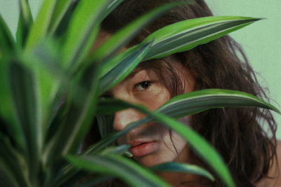 Portrait of young woman looking through plants