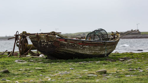 Abandoned boat moored on beach against sky