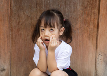 Portrait of cute girl sitting on wood