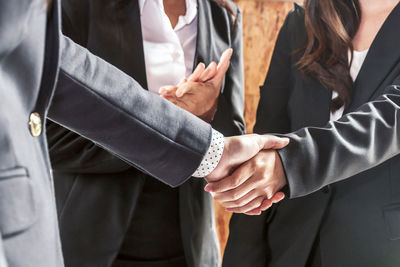 Midsection of woman clapping by colleagues handshaking in office