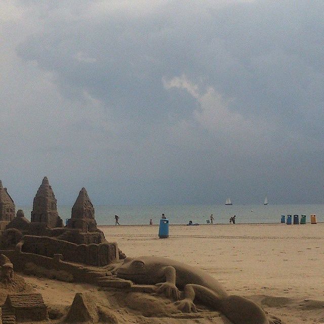 beach, sea, sky, sand, water, shore, cloud - sky, scenics, incidental people, tranquility, horizon over water, tranquil scene, tourism, travel destinations, nature, beauty in nature, travel, rock - object, cloud, built structure