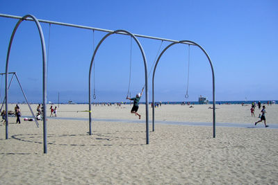 Man playing on beach against clear blue sky