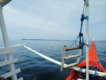 Sailboat tied to pole by sea against sky