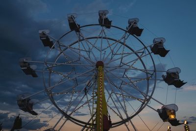 Low angle view of ferris wheel against cloudy sky during sunset