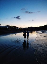 Silhouette men standing in water at sunset