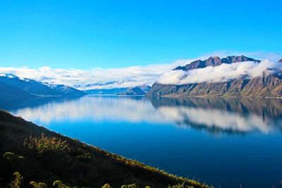 Scenic view of lake and mountains against blue sky