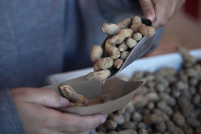 Cropped image of person holding scoop with peanuts
