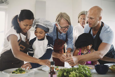 Multi-generational family preparing food at table in kitchen