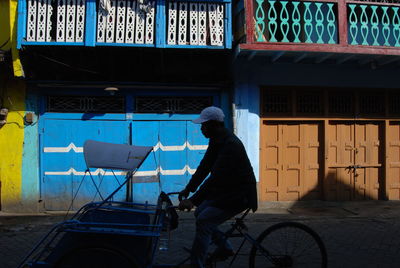 Man riding bicycle on street against building