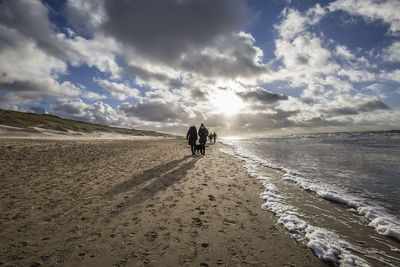 People walking at beach against sky