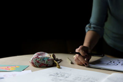 Cropped image of woman writing in book at table