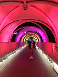 Rear view of woman standing in illuminated tunnel