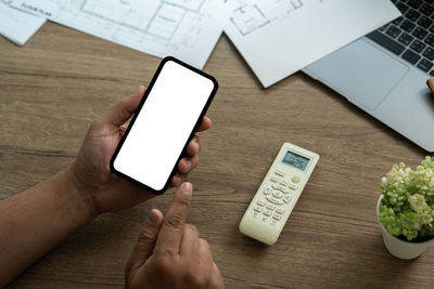 Cropped hands of woman using mobile phone on table