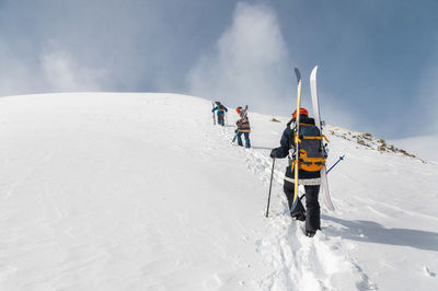 Backcountry climbers, ski climber, walking with skis and snowboard in the mountains. 