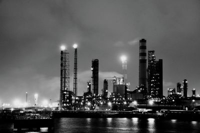 Illuminated factory against sky at night