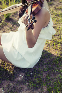 Midsection of woman playing violin on field