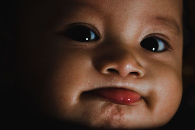 Close-up portrait of cute baby boy against black background