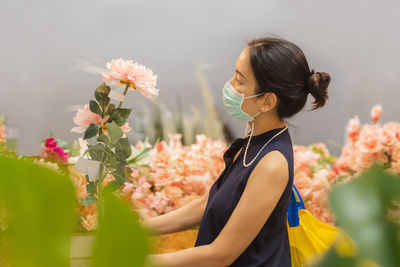 Woman in protective mask buying artificial flowers during covid-19