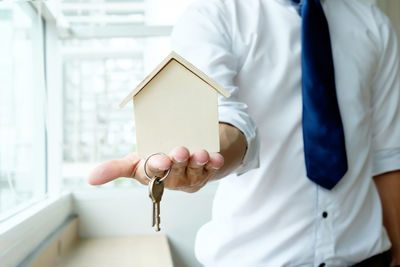 Close-up of man holding model home and keys