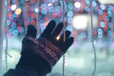 Cropped hand touching string light