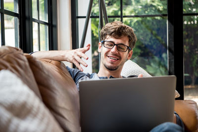 Smiling young man using laptop while sitting at home