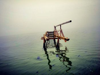 Broken bridge amidst lake during foggy weather