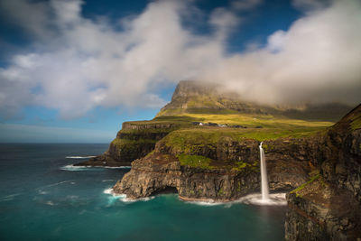 Scenic view of waterfall by sea against sky