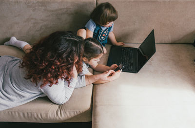 High angle view of woman using phone while sitting on sofa at home