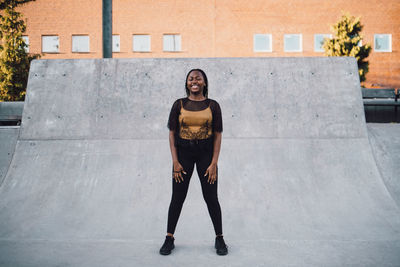 Full length of smiling teenage girl dancing at skateboard park