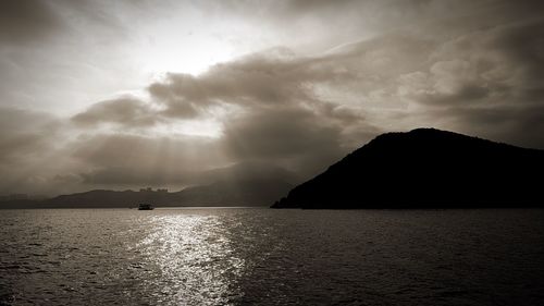 Scenic view of sea by mountain against sky